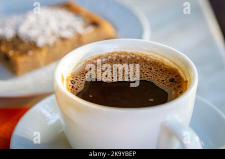 Griechischer Kaffee auf dem Esstisch mit griechischem Kuchen im Hintergrund verschwommen Stockfoto