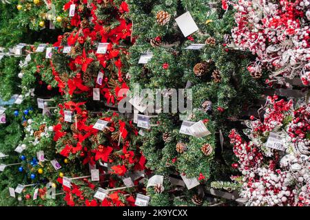 Moskau, Russland, November 2020: Eine große Anzahl von Weihnachtsbaumkränzen mit Dekorationen aus Kugeln, roten Bögen, Pinienzapfen und künstlichen Beeren Stockfoto