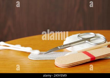 Maniküre-Werkzeuge, Schere, Nagelfeile, Wattestäbchen auf dem Holztisch. Thema Schönheit und Körperpflege Stockfoto