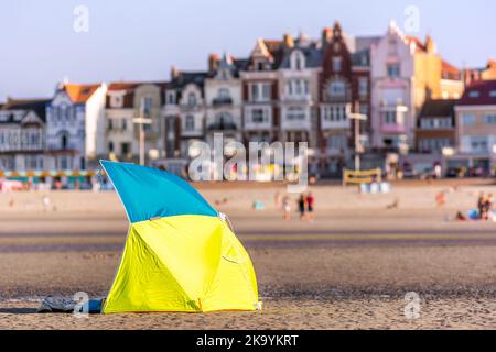 Panoramablick auf den Strand bei Sonnenuntergang mit Sonnenschirm und Blick auf die Stadt im Hintergrund Stockfoto