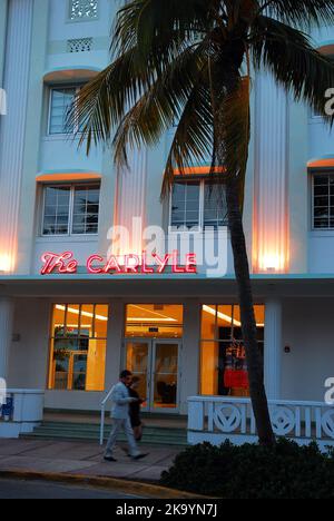 Ein junges Paar geht am Vordereingang des Art déco-Hotels The Carlyle in Miami Beach, Florida, vorbei Stockfoto