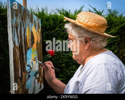 Caen, Frankreich August 2022. Künstlermaler Ältere Frau malt Landschaften. Hobbys, Freizeit, Entspannung. Oma malt Bilder Stockfoto