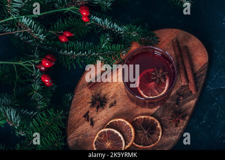 Weihnachtlicher Glühwein mit Gewürzen auf einem Schneidebrett. Draufsicht, flach liegend. Stockfoto