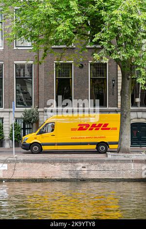 Amsterdam, Niederlande - August 2022: Lieferwagen von DHL, der entlang eines Kanals im Stadtzentrum von Amsterdam fährt Stockfoto