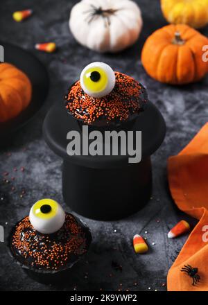 Hausgemachte Halloween Schokolade Cupcakes mit gelben Gelee Augäpfel mit Streuseln, Süßigkeiten und Kürbissen verziert. Selektiver Fokus. Stockfoto