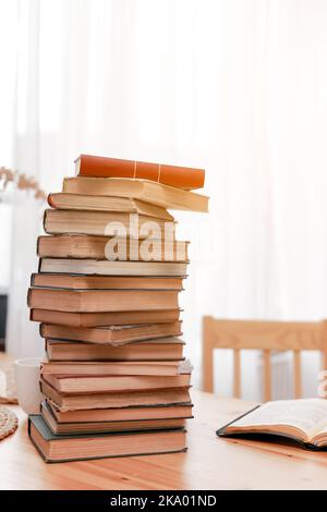 Stapeln Sie Bücher oder Lehrbücher und ein geöffnetes Buch auf einem Holzschreibtisch im Zimmer. Literaturrecherche. Konzept - Informationssuche in Büchern. Zurück zur Schule. Bildung und Schulkonzept. Platz kopieren Stockfoto