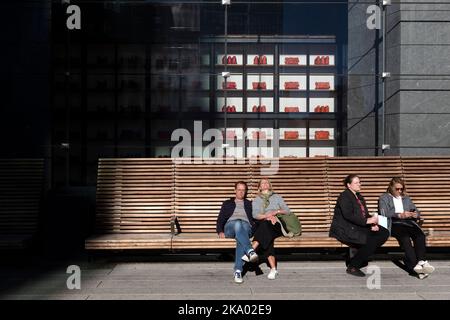 Menschen, die auf einer Bank an der High Line vor dem Coach Store in Hudson Yards, Chelsea, Manhattan, New York sitzen Stockfoto