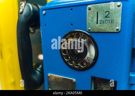 Altes polnisches Vintage-Telefon in einer Kabine. Telefon aus dunkelblauem Metall mit schwarzem Empfänger und Metallzifferblatt. Nahaufnahme. Anfänge der Kommunikation. Hochwertige Fotos Stockfoto