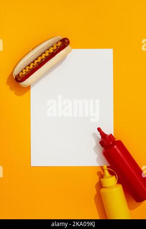 Klassischer Hot Dog mit Wurst, Ketchup und Senf auf orangefarbenem Hintergrund Stockfoto