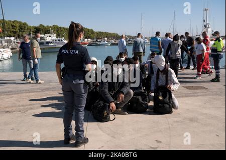 Roccella Jonica, Reggio Calabria, Italien. 30. Oktober 2022. Migranten sahen auf dem Dock warten. 55 Migranten, hauptsächlich aus dem Iran und Afghanistan und aus der Türkei, wurden von der italienischen Küstenwache und der Finanzpolizei gerettet und in 'Porto delle Grazie', dem Hafen von Roccella Jonica, Region Kalabrien (Italien), gebracht. Ärzte ohne Grenzen, Rotes Kreuz und Katastrophenschutz leistten bei der Ankunft Hilfe. (Bild: © Valeria Ferraro/ZUMA Press Wire) Stockfoto