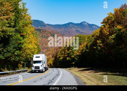 Ein Blick auf Snowy Mountain in den Adirondacks im Herbst von der NYS Route 30 Highway mit einem weißen Sattelschlepper, der den Hügel hinauf fährt. Stockfoto