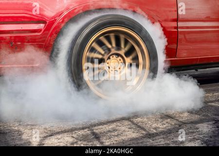 Ziehen Sie den brennenden Reifen des Rennwagens an der Startlinie auf der Rennstrecke Stockfoto