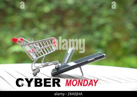 Cyber Monday-Nachricht mit Kreditkarte und Mini-Einkaufswagen auf dem Smartphone. Stockfoto