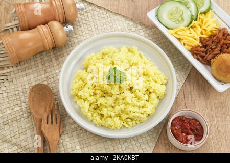 Nasi Kuning, traditionelles indonesisches Essen aus Reis, zubereitet mit Kurkuma und Kokosmilch und Gewürzen, serviert mit verschiedenen Beilagen Stockfoto