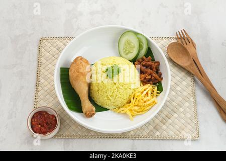 Nasi Kuning, traditionelles indonesisches Essen aus Reis, zubereitet mit Kurkuma und Kokosmilch und Gewürzen, serviert mit verschiedenen Beilagen Stockfoto