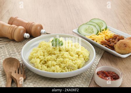 Nasi Kuning, traditionelles indonesisches Essen aus Reis, zubereitet mit Kurkuma und Kokosmilch und Gewürzen, serviert mit verschiedenen Beilagen Stockfoto