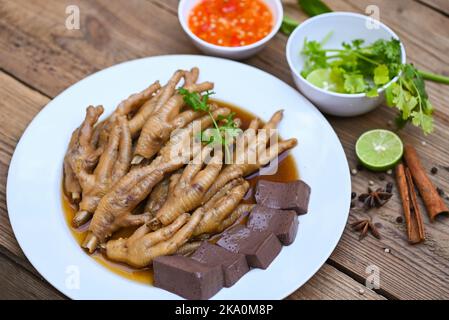Thai-Essen, Hühnerfüße Suppe geschmort, Kochen Hühnerfüße Fuß Eintopf auf weiß mit Kräutern und Gewürzen Zutaten mit Chili Zitrone Gemüse auf Holz b Stockfoto