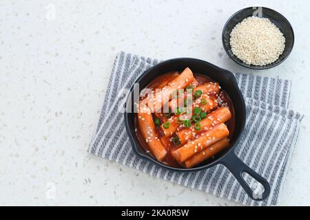 Tteokbokki oder Topokki, gebratener Reis-Kuchenstab, beliebtes koreanisches Street Food mit würziger Gochujang-Sauce und Sesamsamen. Stockfoto