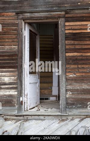 Die offene Tür lädt die Neugierigen ein, die Treppe eines verlassenen Bauernhauses auf der Prärie von Saskatchewan in der Nähe der Stadt Mankota hinauf zu gehen. Stockfoto