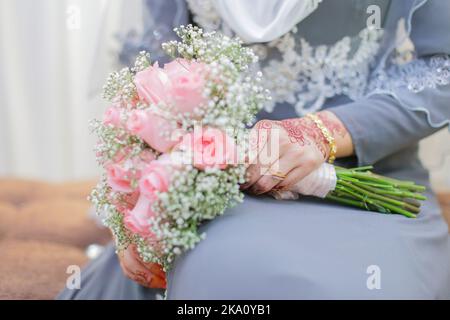 Braut Hand mit Henna und einem Blumenstrauß Stockfoto