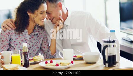 Ihre morgendliche Routine bringt sie zum Glück. Ein liebevolles Paar mittleren Alters, das morgens zu Hause zusammen frühstückt. Stockfoto