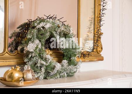 Schöner Weihnachtskranz steht auf Kaminsims mit Dekor.New year Winter Home Inneneinrichtung. Stilvolles, weihnachtlich dekoriertes Zimmer. Stockfoto