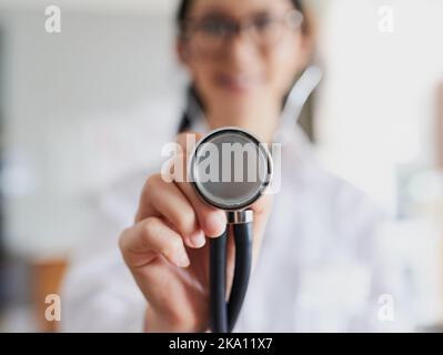 Hören wir diesen Herzschlag. Eine junge Ärztin, die sich mit einem Stethoskop ausstreut, um auf Ihren Herzschlag zu hören. Stockfoto