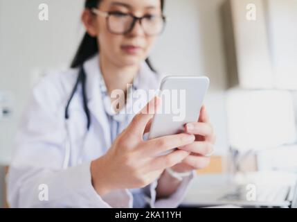 Sie bleibt in Kontakt mit ihren Patienten. Eine junge Ärztin sendet einen Text, während sie im Krankenhaus arbeitet. Stockfoto