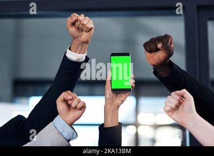 Die App, die Ihr Unternehmen zum Erfolg befähigt. Eine Gruppe von Geschäftsleuten jubelt und hält ein Smartphone in einem modernen Büro. Stockfoto