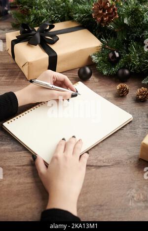 Hände einer Frau, die die Weihnachts-Wunschliste schreibt, Ansicht von oben Stockfoto