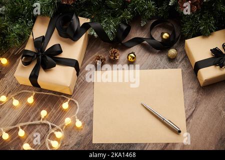 Geschenke, Weihnachtslichter und leeres Blatt Papier auf dem Tisch, Blick von oben Stockfoto