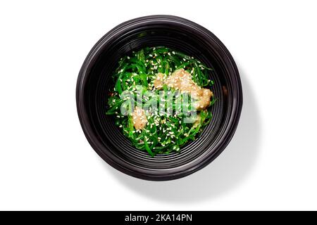 Traditioneller japanischer Hiyashi-Wakame-Salat mit Erdnusssauce und Sesam in schwarzer Schüssel Stockfoto