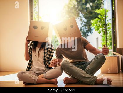 Moving Day Sillness. Ein Paar trägt Boxen mit Smiley Gesichter auf ihnen auf dem Kopf gezeichnet. Stockfoto