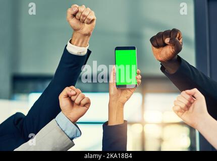 Tun Sie es jetzt, und laden Sie es für Ihr Unternehmen. Eine Gruppe von Geschäftsleuten jubeln und halten ein Mobiltelefon in einem modernen Büro. Stockfoto