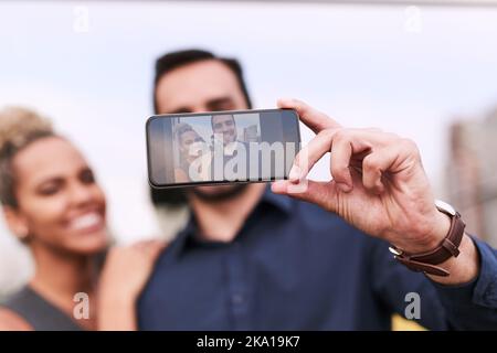Pausenzeit bedeutet eine Chance für einige Selfies. Nahaufnahme von zwei Kollegen, die vor einem Büro zusammen ein Selfie machen. Stockfoto