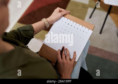 Über dem Winkel der weiblichen Tutorin mit Tabellenkalkulation der chinesischen Hieroglyphen Überprüfung Papier der Schülerin oder erklären neues Thema in der Lektion Stockfoto