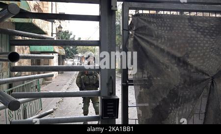 Bewaffnete israelische Soldaten schließen am 30. Oktober 2022 in Hebron, Israel, das Tor des Grenzübergangs Bab El-Zawiya zwischen dem palästinensischen Viertel Bab A-Zawiya und dem israelischen Kontrollgebiet H-2. Stockfoto