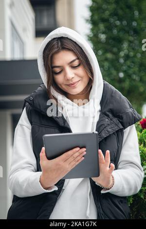 Glückliche junge Frau verwendet ein Tablet und lächelt. Stockfoto