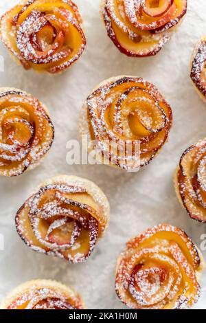 Gebackene Apfelkuchen in Form von Rosen mit Zimt und Nelken auf einer Backform Stockfoto