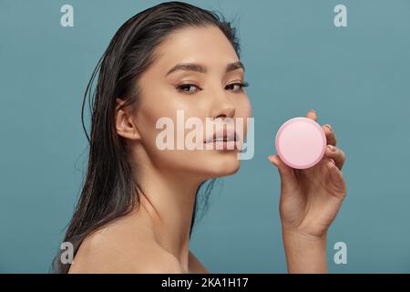 Kopfschuss Porträt der asiatischen Mädchen mit runden Creme-Glas. Stockfoto