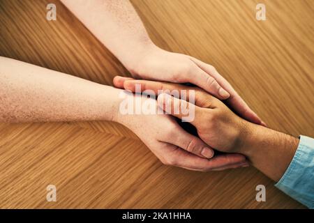 Du bist jetzt in einem sicheren Raum. Ein Mann und eine Frau halten die Hände bequem auf einem Tisch. Stockfoto