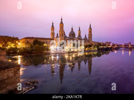 Die malerische Landschaft mit der Basilika El Pilar in Zaragoza bei Sonnenaufgang spiegelt sich im Ebro-Fluss wider Stockfoto