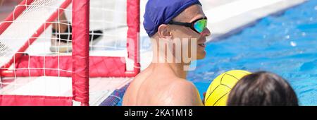 Mann am Tor im Pool spielt Wasserball. Stockfoto