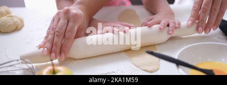 Mama und Tochter Rollen den Teig mit Nudelholz in der Küche aus Stockfoto