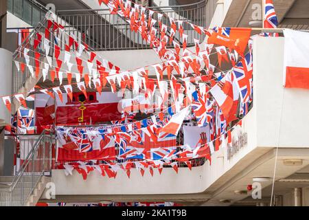 Viele rot-weiße Streifen mit Nationalflaggen, die über die Treppe eines Wohnblocks in Gibraltar hingen. Stockfoto