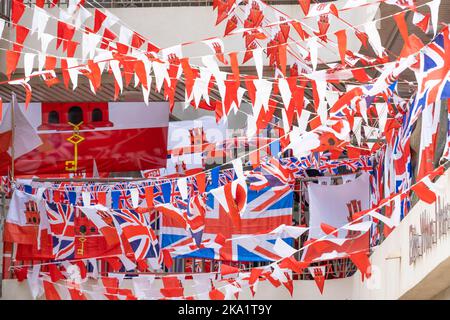 Viele rot-weiße Streifen mit Nationalflaggen, die über die Treppe eines Wohnblocks in Gibraltar hingen. Stockfoto