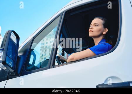 Schöne Frau professionelle LKW-Fahrer sitzen innerhalb Cargo-Auto während der Lieferung. Frauen in männlich dominierten Branchen und Berufen Stockfoto
