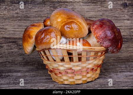 Voller Korbkorb mit Steinpilzen auf einem hölzernen Hintergrund, Nahaufnahme Stockfoto