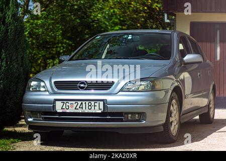 Silberblau 2002 Opel Vauxhall Astra geparkt vor der Hausgarage an sonnigen Tag außen Stockfoto
