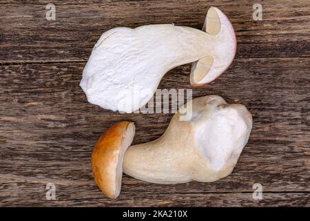 Zwei Hälften eines weißen Pilzes auf einem hölzernen Hintergrund, Nahaufnahme Stockfoto